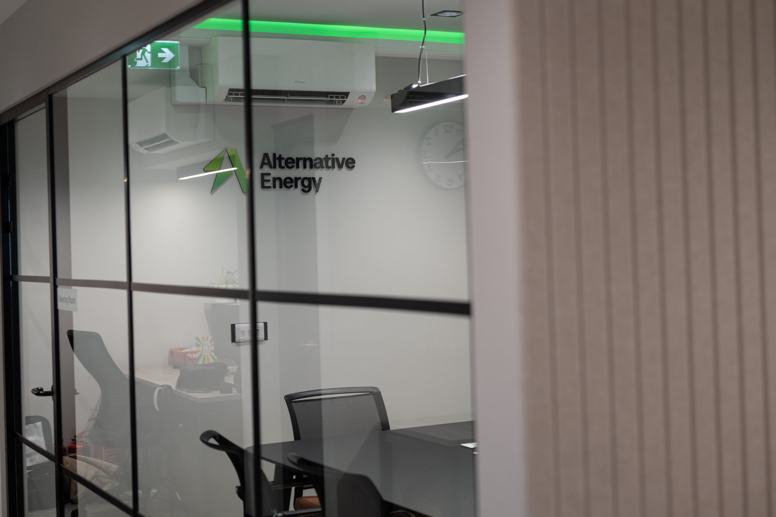 Photo of Alternative Energy's boardroom, featuring branding signs on the wall, green LED accent lighting and office furniture