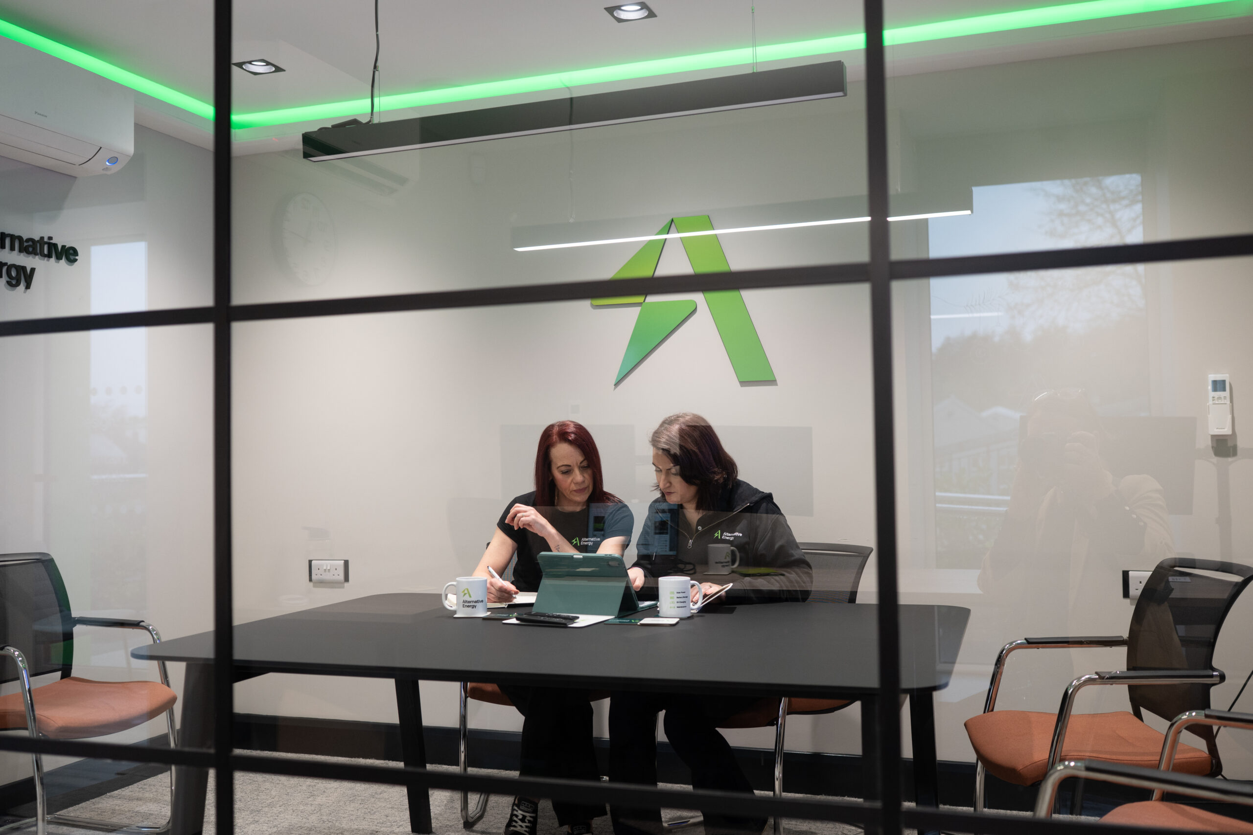 two female employees working collaboratively in the alternative energy boardroom.